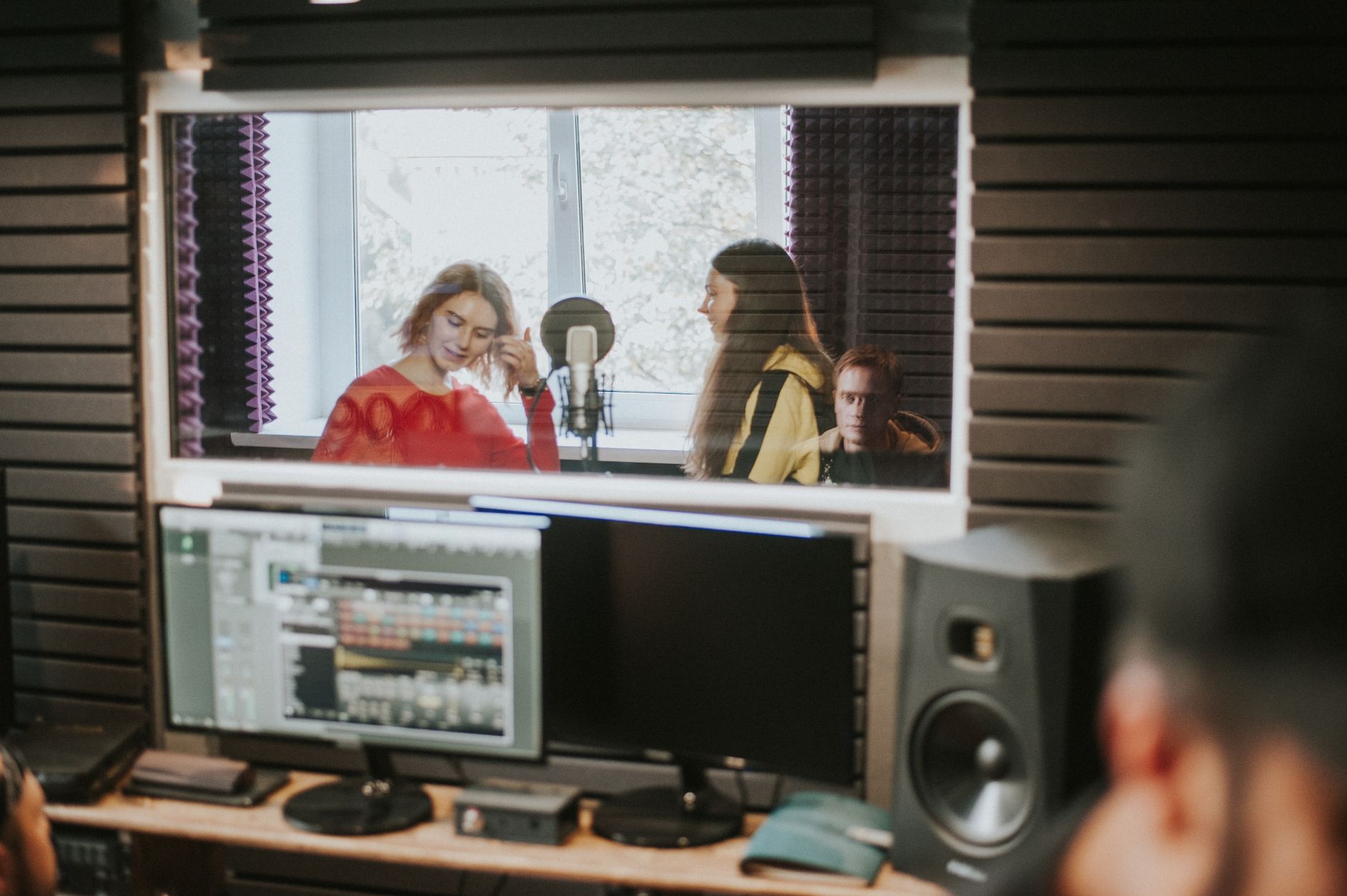 studio monitor pair on desk near treated wall acoustic foam